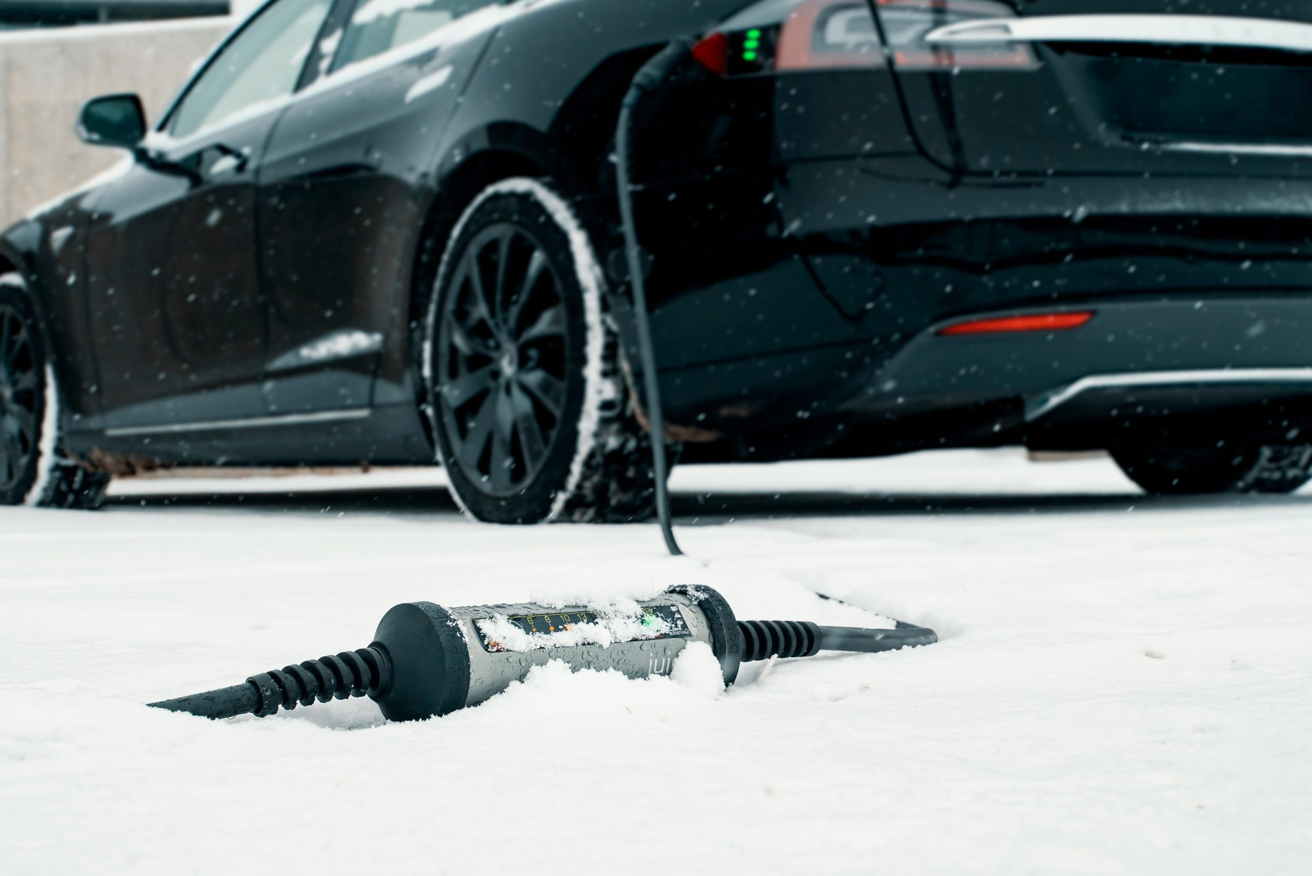 Black Tesla Charging in Snowy Weather