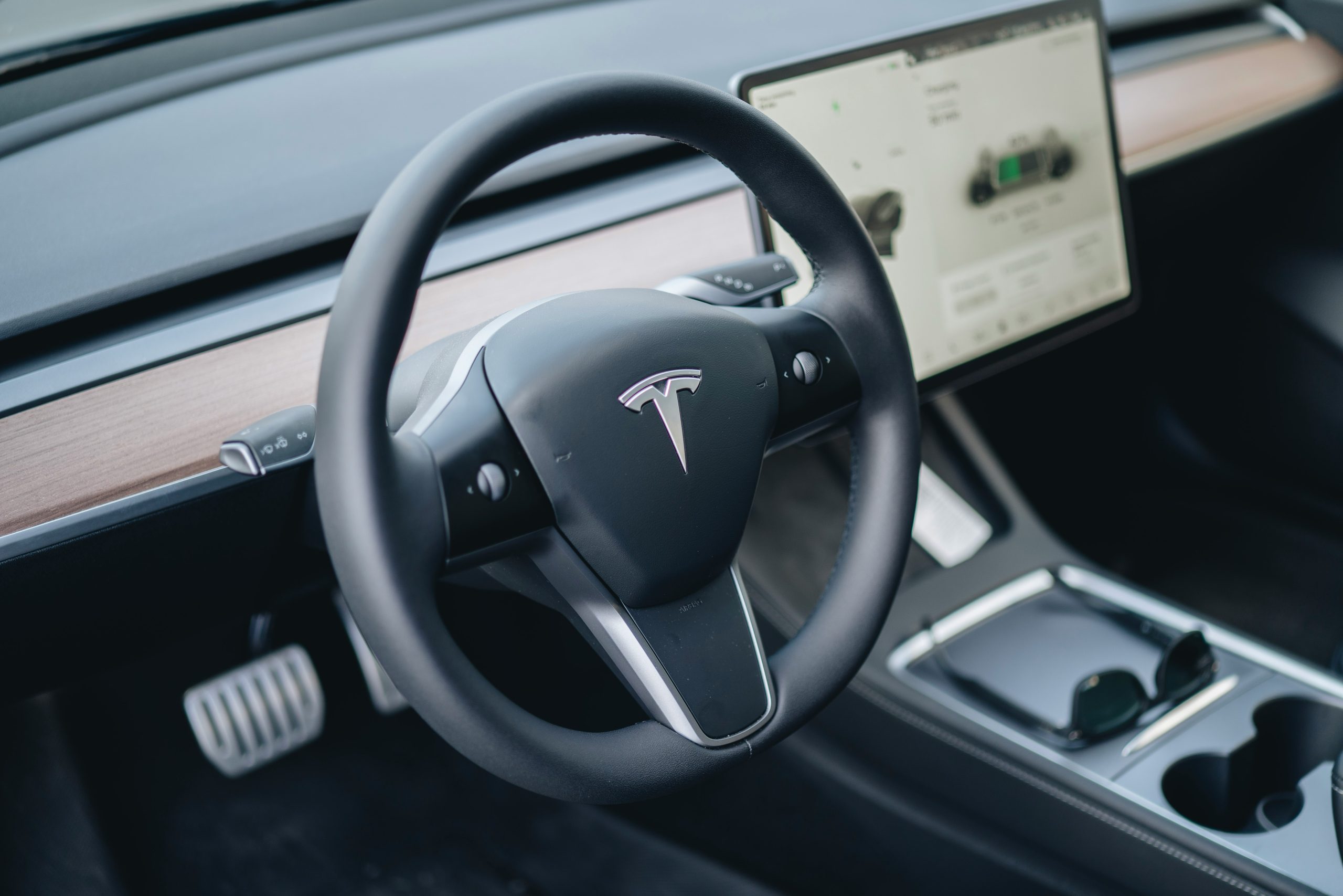 Interior of a Tesla, Showing the Steering Wheel, Centre Console, Dashboard, and Touchscreen